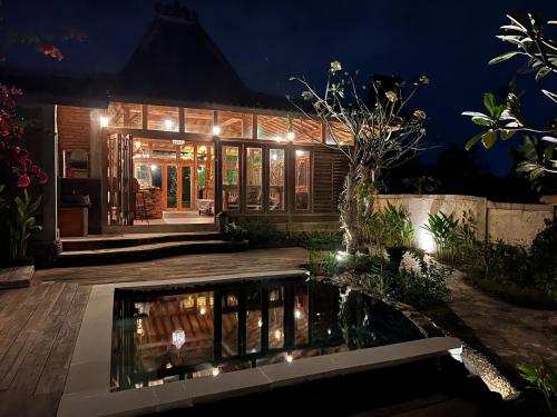 a house with a pond in the yard at night at PINOKKIO B&B Restaurant in Jimbaran