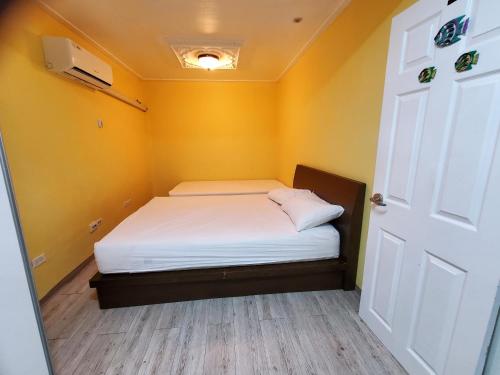 a small bedroom with a bed in a room with yellow walls at Daora guesthouse in Garapan