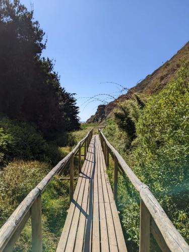 a wooden bridge over the water on a beach at Depto en Costa Algarrobo Norte con wifi in Algarrobo