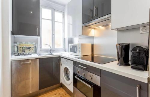 une cuisine équipée d'appareils électroménagers en acier inoxydable et d'un lave-linge/sèche-linge dans l'établissement Beautiful apartment in center Paris, à Paris