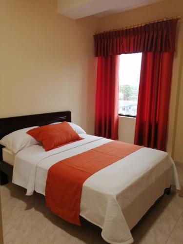 1 dormitorio con 1 cama con cortinas rojas y ventana en Hotel Torre Orquídea en Puerto Francisco de Orellana