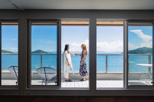 two women standing on a balcony looking out at the ocean at SETOUCHI SUP RESORT - Ao - in Shodoshima