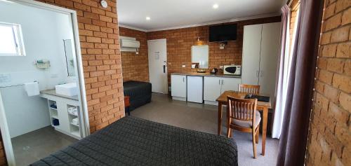 a room with a bed and a table and a kitchen at Centrepoint Motel Deniliquin in Deniliquin