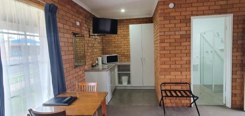a kitchen with a brick wall and a table and chairs at Centrepoint Motel Deniliquin in Deniliquin