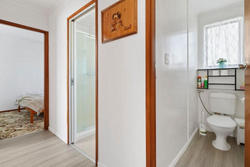 La salle de bains est pourvue de toilettes et d'un miroir. dans l'établissement Family 3BR Home with Netflix and Fully Fenced Yard, à Auckland