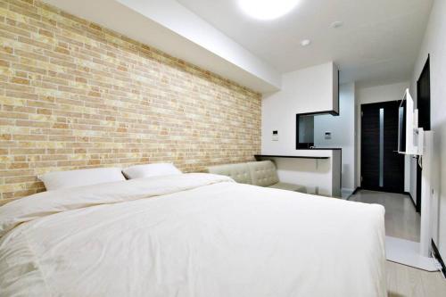 1 dormitorio con cama blanca y pared de ladrillo en Green Sea Oshiage, en Tokio