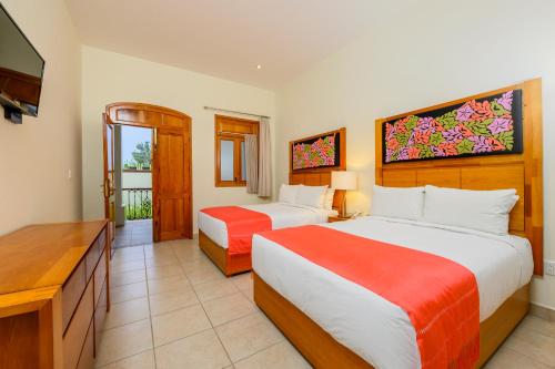 a hotel room with two beds and a television at XTILU Hotel - Adults only - in Oaxaca City