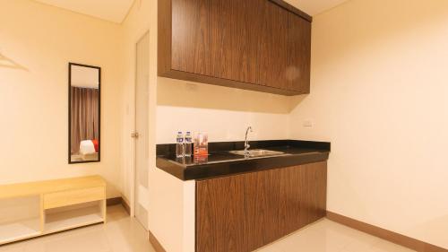 uma cozinha com um lavatório e armários de madeira em RedDoorz Plus @ Kaizen Suites Taft Avenue em Manila