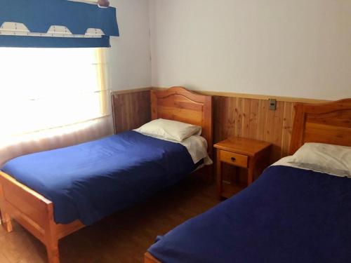 a bedroom with two beds and a window at Cabañas Ruka Rayun vista y acceso al lago en Coñaripe in Panguipulli