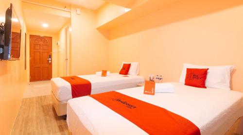 um quarto de hotel com duas camas com lençóis laranja e branco em RedDoorz Plus @ Kaizen Suites Taft Avenue em Manila