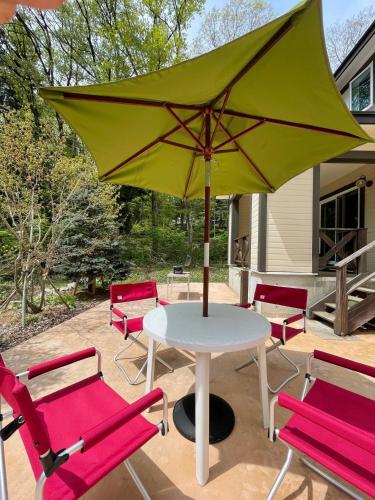 a table and chairs with a green umbrella on a patio at Alps Retreat Chalet by Morino in Hakuba