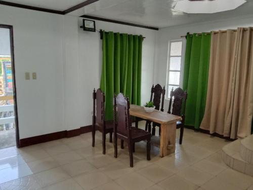comedor con cortinas verdes, mesa y sillas en RedDoorz @ Isla Virginia Beach Resort Aurora Baler, en Baler