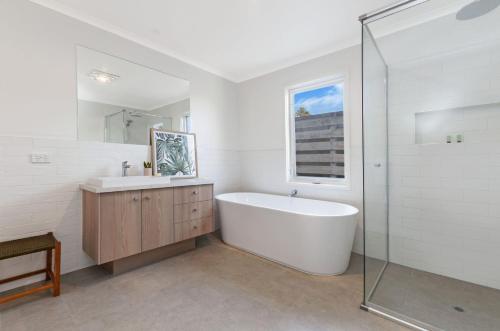 a white bathroom with a tub and a sink at Lyons in Port Fairy
