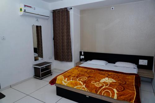 a bedroom with a bed with an orange blanket at Heaven Accommodations in Rajkot