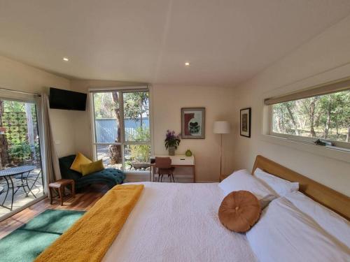 a bedroom with a large white bed and windows at Bellshala bungalow in Bellbrae