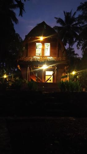 une maison éclairée la nuit avec des lumières dans l'établissement Rumah Saung Batukaras, à Batukaras