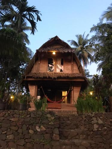 uma casa com um telhado de palha no topo de uma parede de pedra em Rumah Saung Batukaras em Batukaras