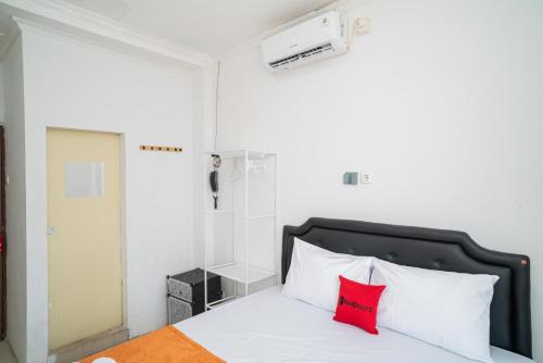ein Schlafzimmer mit einem Bett mit einem roten Kissen in der Unterkunft RedDoorz @ Aralia Harapan Indah in Pulokendal