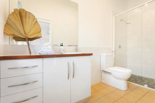 a white bathroom with a toilet and a sink at Fuller Holidays - Hacienda, Luxury 5 bedroom home with pool in Byron Bay