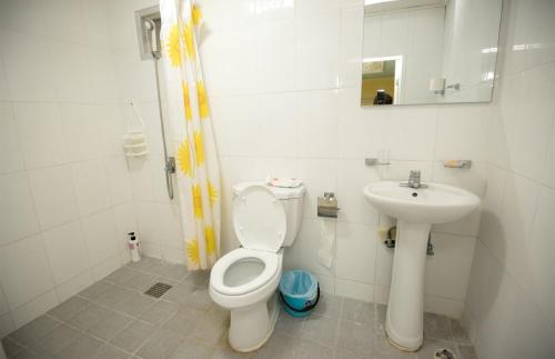 a white bathroom with a toilet and a sink at Daora guesthouse in Garapan