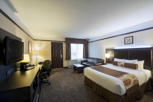 a hotel room with a bed and a television at L'Escale Hôtel Suites in Val-dʼOr