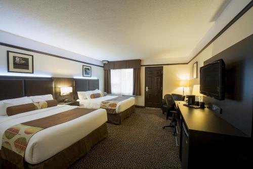 a hotel room with two beds and a flat screen tv at L'Escale Hôtel Suites in Val-dʼOr
