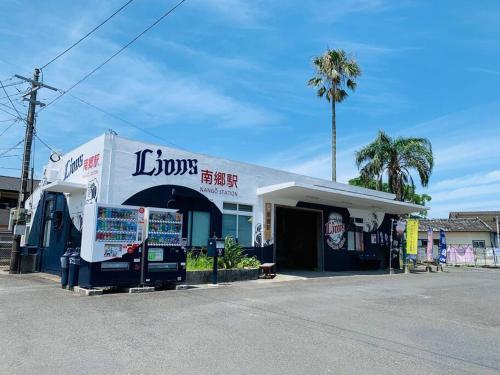 a josys shop with a palm tree in front of it at 格安素泊まり宿南郷駅徒歩3分好立地の一軒家丸々貸しサイクルシーズン南郷 in Meitsu