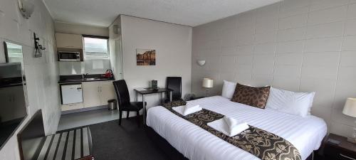 une chambre d'hôtel avec un lit et une cuisine dans l'établissement Forgotten World Motel, à Taumarunui