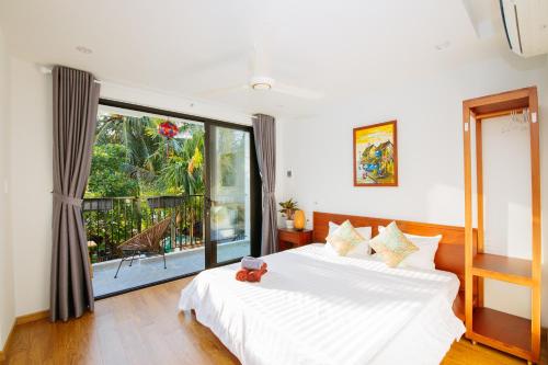 1 dormitorio con cama blanca y ventana grande en Beach Forest Villa, An Bang, Hoi An, en An Bàn (2)