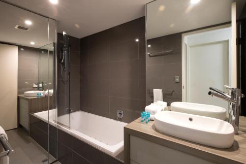 a bathroom with a tub, sink and mirror at Noosa Shores Resort in Noosa Heads