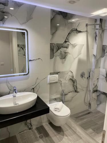 a bathroom with a sink and a toilet and a mirror at Dani's Apartments in Sarandë