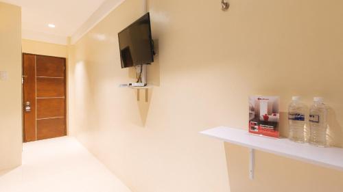 a bathroom with a tv on a wall with bottles of water at RedDoorz at Laiya Vivo Hotel Batangas in San Juan
