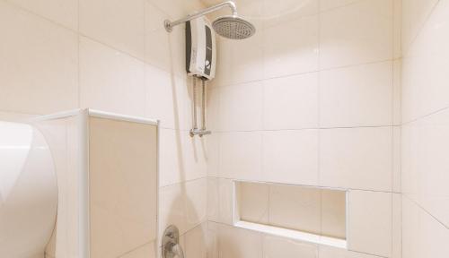 a white bathroom with a shower and a shower head at RedDoorz at Laiya Vivo Hotel Batangas in San Juan