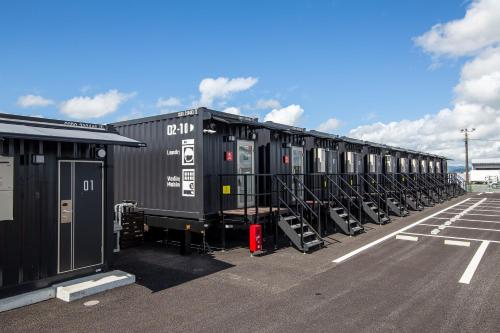 una fila de contenedores de transporte en un estacionamiento en HOTEL R9 The Yard Miyakonojo en Miyakonojō