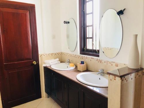 a bathroom with two sinks and two mirrors at Cinnamon Villa in Matara