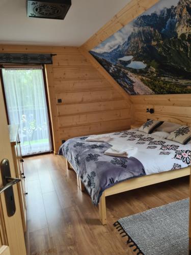 1 dormitorio con 1 cama con una pintura en la pared en Apartament u Jarząbków, en Ciche