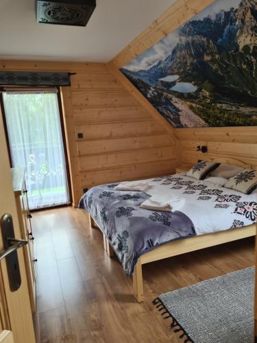 Un dormitorio con una cama con un cuadro en la pared. en Domek u Jarząbków, en Ciche
