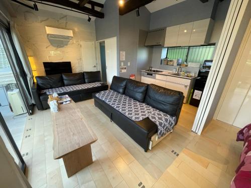 a living room with a black leather couch and a table at KandoStay 伊豆高原パークガーデン in Ito