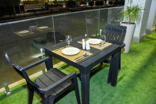 a black table with two chairs and a table with glasses at Ramada by Wyndham Turkistan in Türkistan