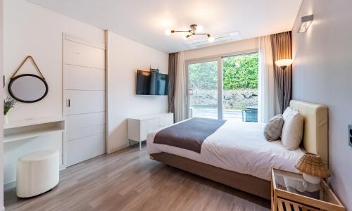 a bedroom with a large bed and a window at Pool and Villa Sorang in Jeju
