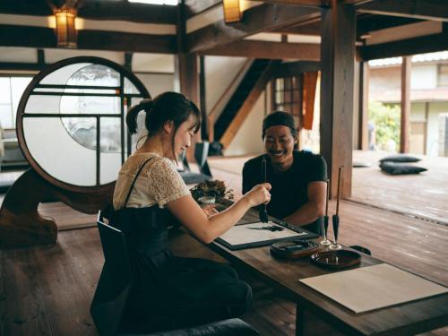 a man and a woman sitting at a table at Kominkayado LOOF Shonoie in Minobu