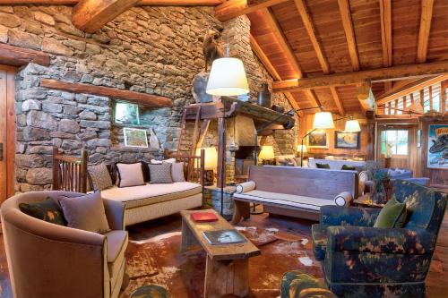 a living room with couches and a stone wall at Hotellerie De Mascognaz in Champoluc