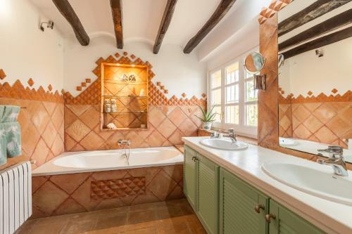 La salle de bains est pourvue de 2 lavabos, d'une baignoire et d'une fenêtre. dans l'établissement Lidia Rural House, à San Martín Sarroca