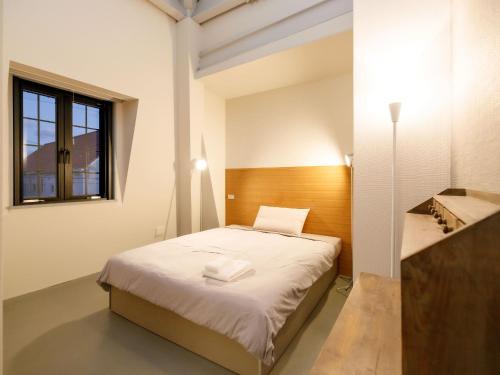 a small bedroom with a bed and a window at Denpaku Akakina Hotel in Amami