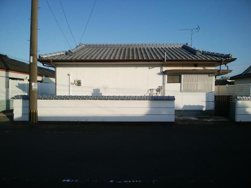 un bâtiment blanc avec un toit noir dans l'établissement みのる民泊1号, à Shibushi