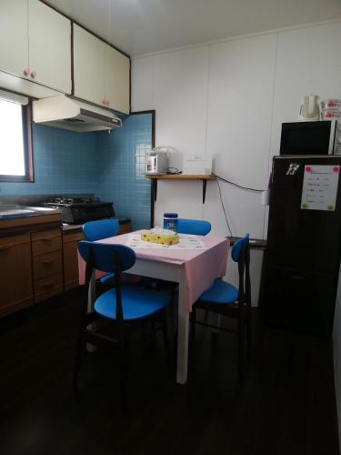 a kitchen with a table with blue chairs and a refrigerator at みのる民泊1号 in Shibushi