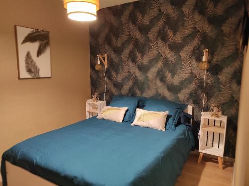 a bedroom with a blue bed with two pillows at Gîte des 3 arbres in Aramits