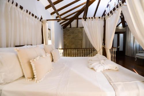 a bed with white sheets and pillows in a room at Torre do Rio in Caldas de Reis