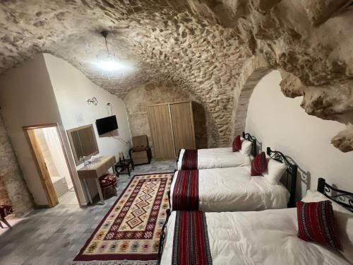 una camera con quattro letti in una stanza con pareti in pietra di Qandeel - Dar Botto a Bethlehem