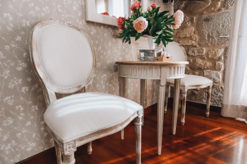 two white chairs and a table with a vase of flowers at Torre do Rio in Caldas de Reis